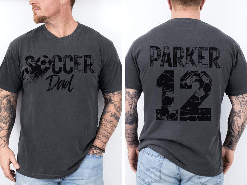 May include: A dark gray t-shirt with the text "Soccer Dad" and a soccer ball graphic on the front. The back of the shirt has the text "Parker 12" with a soccer ball graphic.