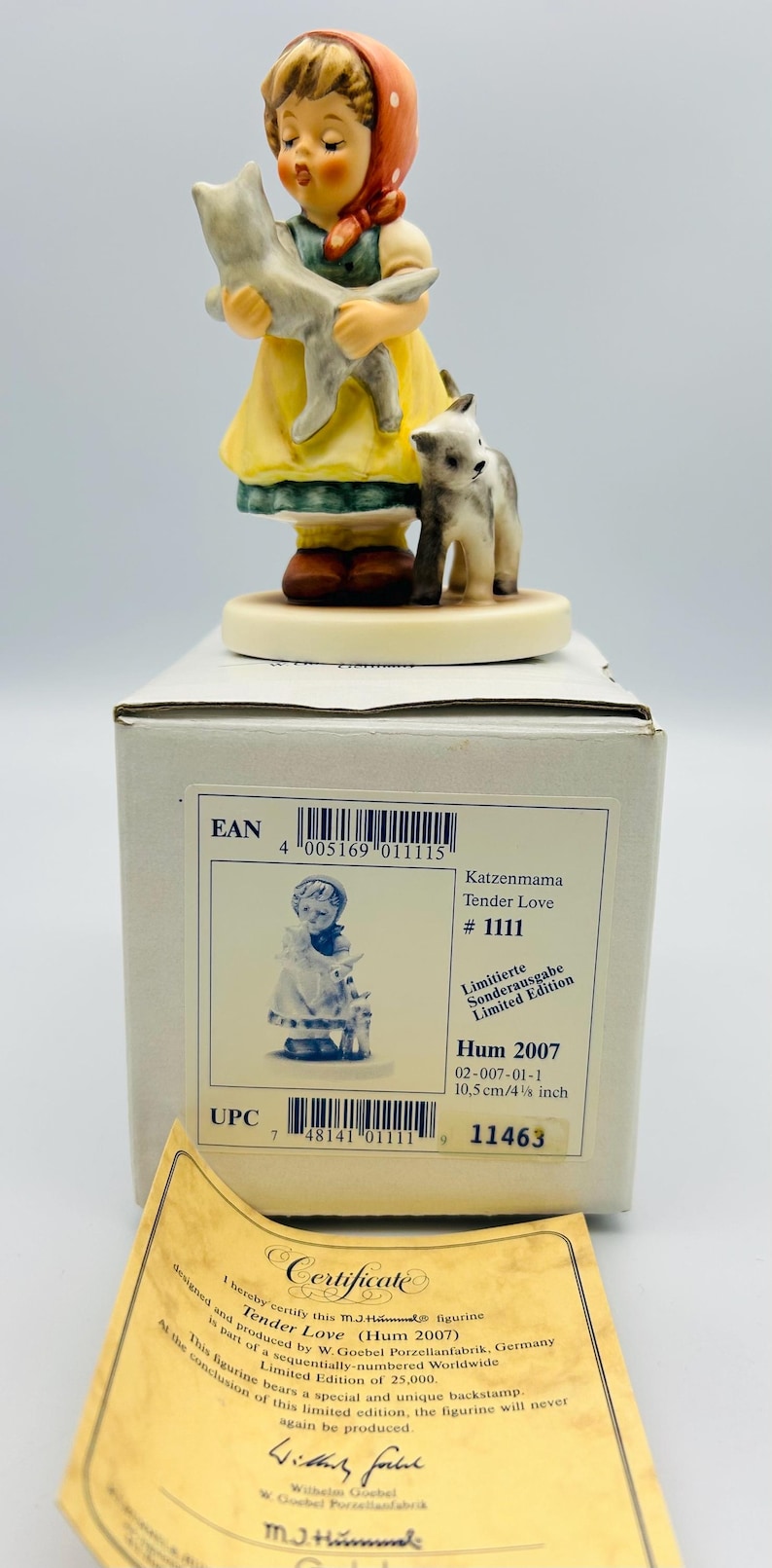 May include: A porcelain figurine of a girl in a yellow dress and red headscarf holding a gray cat, with another cat at her feet. The figurine is on a round base, with a box and certificate in the background. The box has the text "Tender Love #1111".