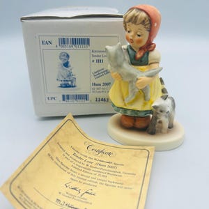 May include: A porcelain figurine titled "Tender Love" depicts a young girl in a yellow dress holding a gray cat, with another cat at her feet. The figurine is part of a limited edition, with a certificate and box visible.