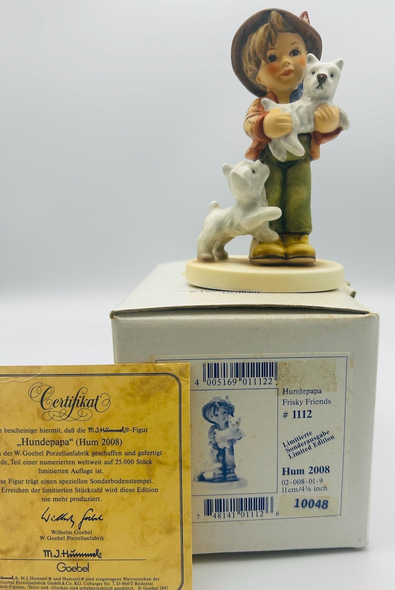 May include: A Hummel figurine titled "Hundepapa" (Hum 2008), depicting a young person holding a white dog, with another dog at their feet. The figurine is part of the "Frisky Friends" series, limited edition, and measures 4 3/8 inches.