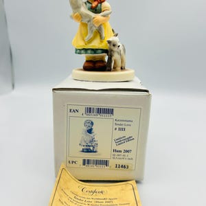 May include: A porcelain figurine titled "Tender Love" depicts a young girl in a yellow dress and red headscarf holding a gray cat, with a small cat at her feet. The figurine is on a round base and comes with a certificate and box.