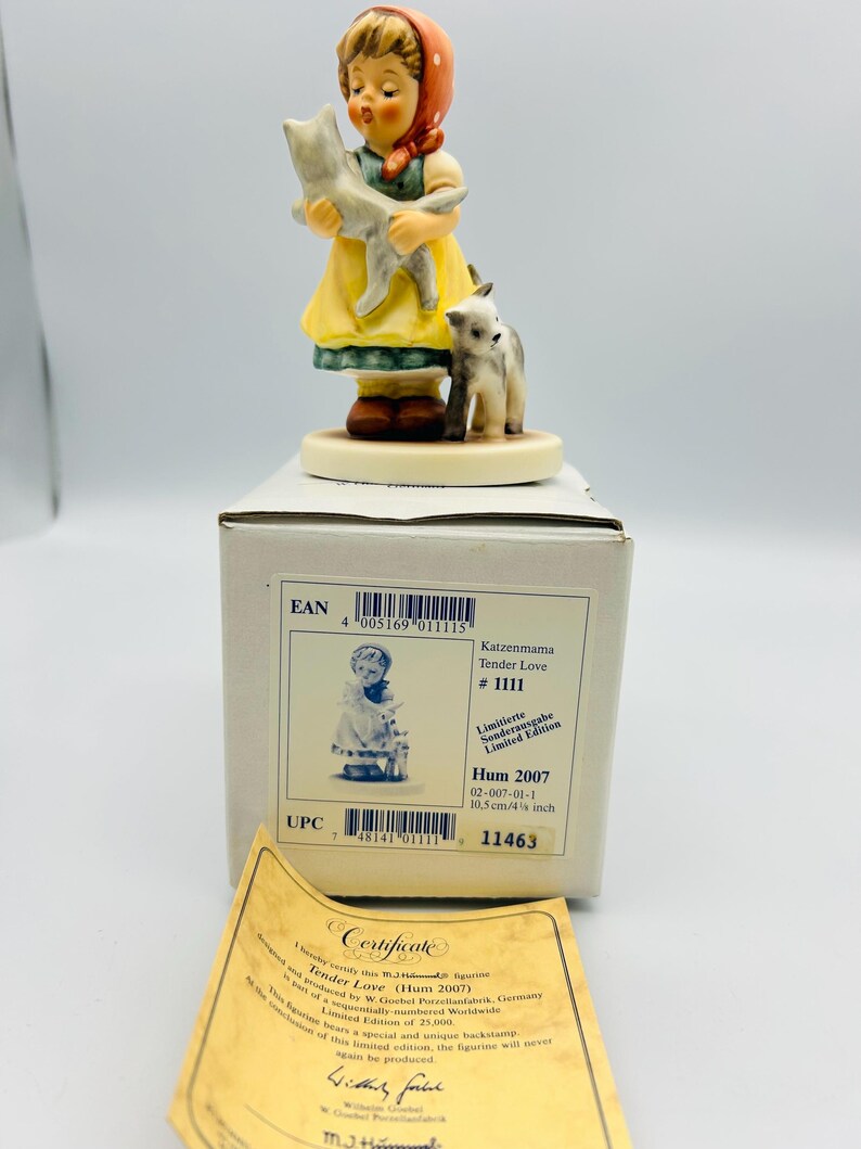 May include: A porcelain figurine titled "Tender Love" depicts a young girl in a yellow dress and red headscarf holding a gray cat, with a small cat at her feet. The figurine is on a round base and comes with a certificate and box.