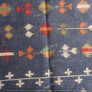 May include: A blue and white patterned rug with a geometric design. The rug has a dark blue background with white and orange accents.