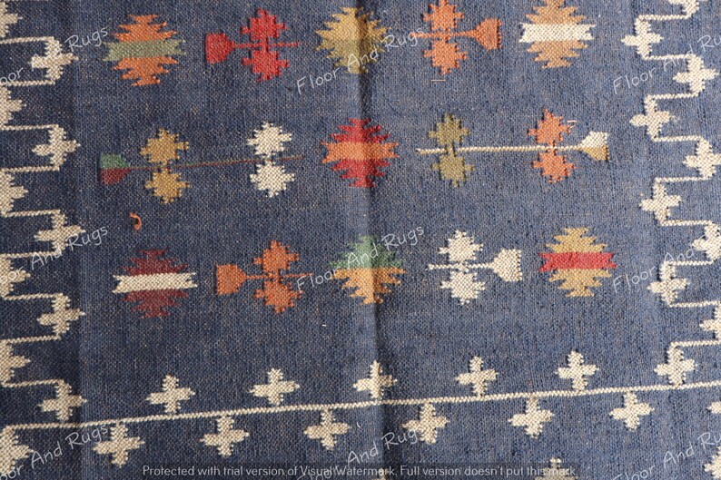 May include: A blue and white patterned rug with a geometric design. The rug has a dark blue background with white and orange accents.