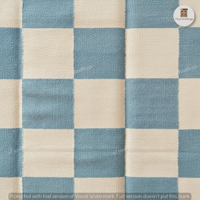 May include: A textile rug featuring a repeating checkerboard pattern in alternating squares of dusty blue and off-white. The fabric has a visible woven texture with a soft, slightly fuzzy surface appearance throughout the entire square grid design.
