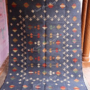 May include: A blue and white wool rug with a geometric pattern. The rug has a fringe border and is made of natural fibers.