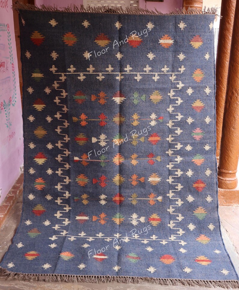 May include: A blue and white wool rug with a geometric pattern. The rug has a fringe border and is made of natural fibers.