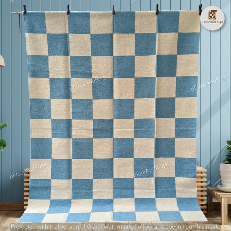 May include: A rectangular area rug featuring a repeating checkered pattern of alternating light blue and off-white squares. The rug is displayed hanging vertically, showcasing a consistent grid design across its entire surface area.