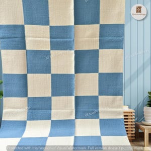 May include: A rectangular rug featuring a repeating checkered pattern of alternating light blue and off-white squares. The textile has a visible woven texture throughout the surface. The text FloorAndRugs is printed in small letters across the rug.