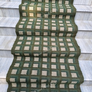Può includere: Tappeto per scale a motivi verdi e beige. Il tappeto presenta un motivo quadrato ripetuto nelle tonalità del verde e del beige. Il testo "Floor And Rugs" è visibile sul tappeto.