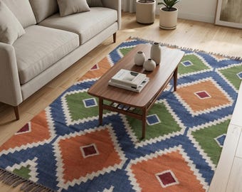 May include: A rectangular area rug featuring a repeating diamond pattern in blue, orange, and green with white borders. The rug has a fringe trim on the short ends and a multi-colored geometric design with small dark red squares in the center.
