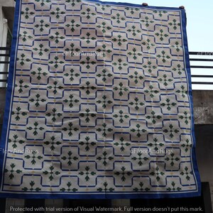 May include: A rectangular rug featuring a cream-colored base with a repeating grid pattern of dark blue lines. Within each grid square is a dark green floral motif and small yellow accents. The rug is finished with a solid dark blue border.