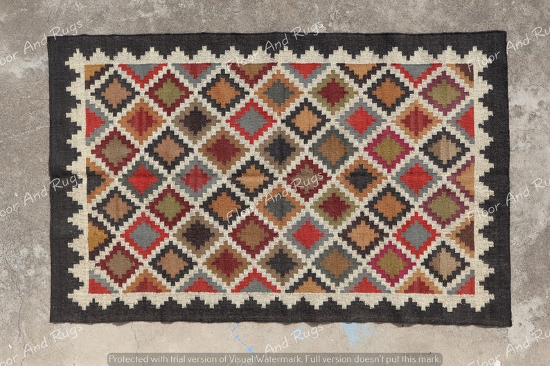 May include: A rectangular area rug featuring a repeating diamond pattern in shades of red, green, brown, and gray. The rug is framed by a cream-colored zigzag border and a solid black outer edge, creating a distinct geometric design throughout.