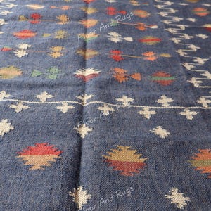 May include: A blue and white handwoven rug with a geometric pattern. The rug has a fringe border and is made of natural fibers.
