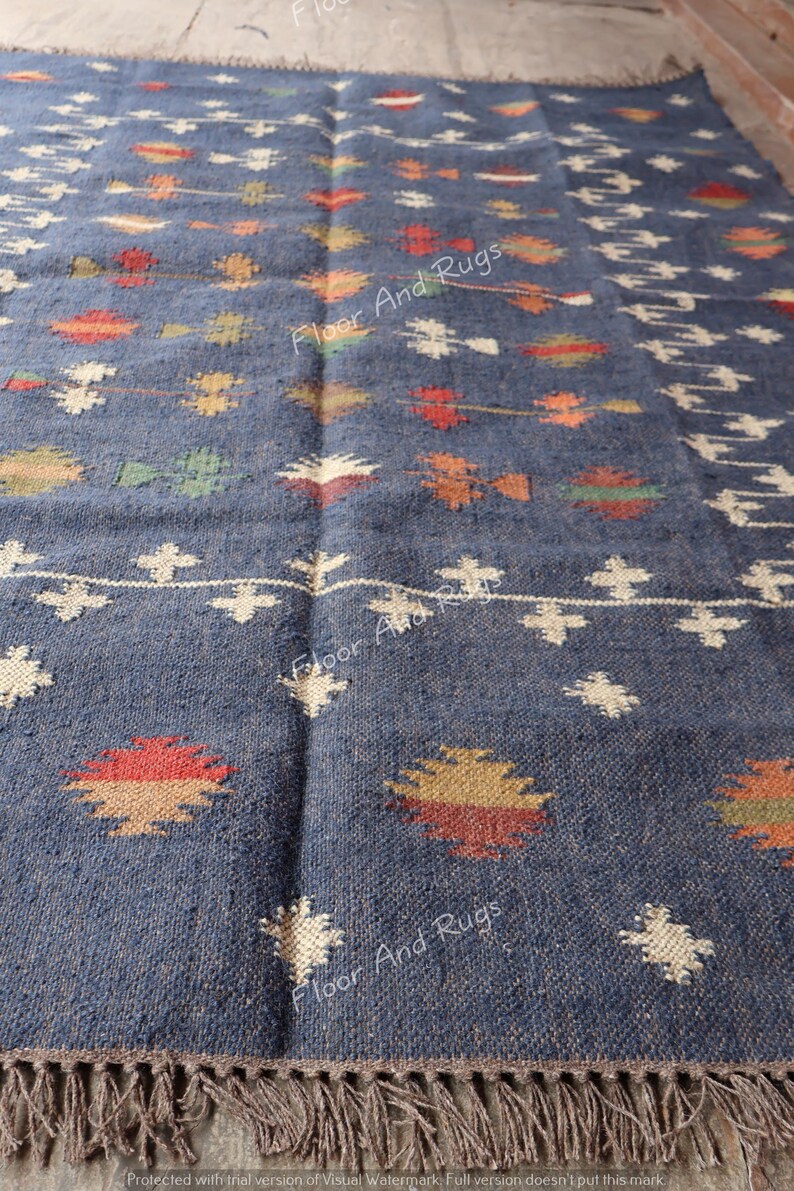 May include: A blue and white handwoven rug with a geometric pattern. The rug has a fringe border and is made of natural fibers.