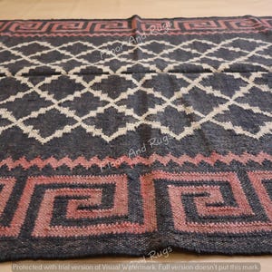 May include: A rectangular area rug featuring a dark charcoal background with a white diamond lattice pattern. The border displays a repeating pink Greek key motif separated by a zigzag line. The text Floor And Rugs is visible across the surface.