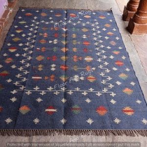 May include: A blue and white patterned rug with a geometric design. The rug has a fringe border and is made of wool.