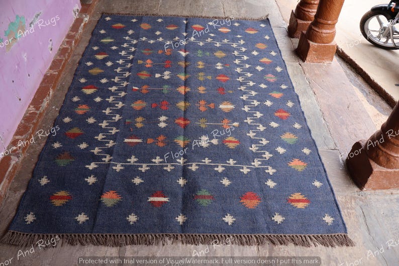 May include: A blue and white patterned rug with a geometric design. The rug has a fringe border and is made of wool.