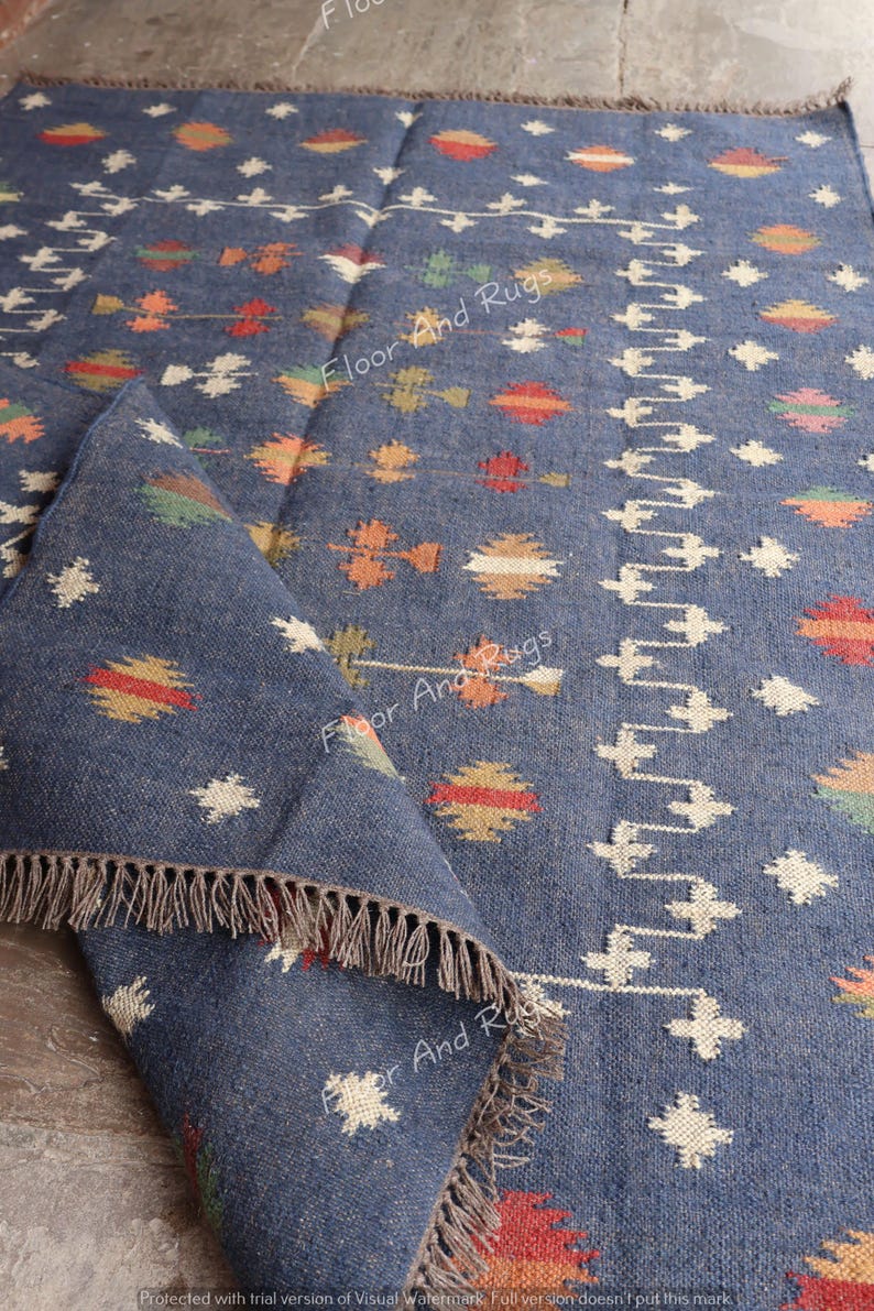May include: A blue and white handwoven rug with a geometric pattern. The rug has a fringe border and is made of natural fibers.