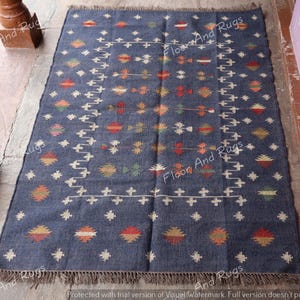 May include: A dark blue rug with a geometric pattern in shades of orange, red, yellow, and white. The rug has a fringe border.