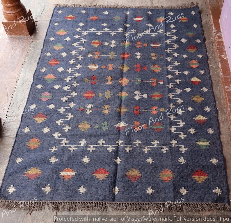 May include: A dark blue rug with a geometric pattern in shades of orange, red, yellow, and white. The rug has a fringe border.