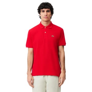 Può includere: Una polo rossa con maniche corte e colletto. La maglia ha una paramontura a due bottoni e un piccolo logo verde a forma di coccodrillo sul petto. Il modello indossa pantaloni color cachi.