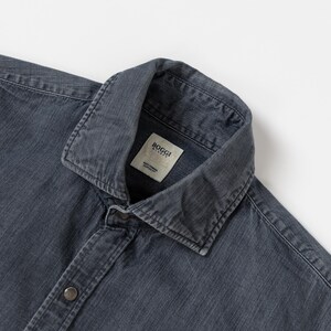 May include: A dark gray long-sleeve shirt with a spread collar and a button-down front. The shirt features a visible fabric texture and a white interior neck label that reads Boggi Milano Easy Formal Custom Fit in black text.