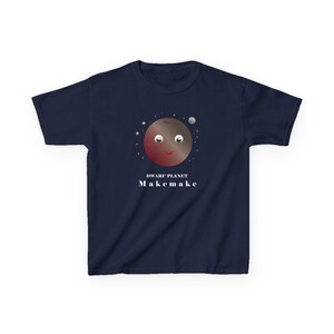 May include: Navy blue t-shirt featuring a cartoon illustration of the dwarf planet Makemake. The planet has a smiling face and is surrounded by stars and a small moon. The text "DWARF PLANET" and "Makemake" are printed below the planet.