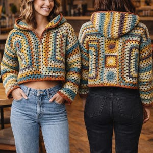 May include: Two women wearing colorful, cropped crochet hoodies with a zip-up front and a hood. The hoodies feature a patchwork design in shades of blue, yellow, orange, and brown. They are paired with blue and black jeans.