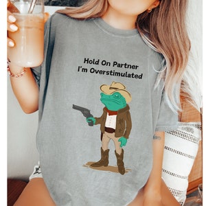 Hold On Partner I&#39;m Overstimulated Shirt, Comfort Colors® Cowboy Frog T-Shirt, Funny Meme Shirt with Trending Quotes In Vintage Design Style
