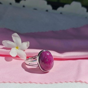 Peut inclure: Une bague en argent avec une grande pierre précieuse ovale rose sertie dans un sertissage à  bezel.