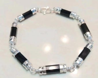 May include: A silver bracelet with black cylindrical beads. The bracelet has a silver clasp.