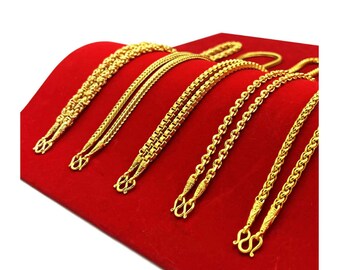 May include: Six gold chains of different styles and lengths displayed on a red velvet surface.