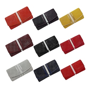 Puede incluir: Nueve bolsos de mano de diferentes colores. Cada uno tiene una superficie texturizada y una banda decorativa plateada con pedrería transparente. Los colores incluyen rojo, negro, amarillo, burdeos, gris, azul marino y otros.