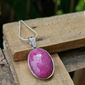 Op de afbeelding: Een zilveren ketting met een roze ovale hanger, gezet in zilver met heldere zirkonia-accenten.