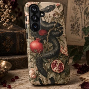 Peut inclure: Une coque de smartphone ornée d'une illustration détaillée d'un serpent sombre enroulé parmi des branches de grenadier, des grenades rouges et des fleurs pâles sur un fond crème, avec une découpe pour triple objectif photo en haut.