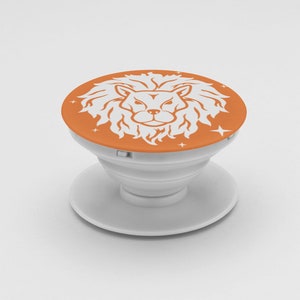 May include: A white and orange phone grip with a lion's head design. The round top features a white lion's head on an orange background, with small star accents. The grip is white and has a collapsible design.