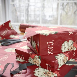 May include: A stack of red gift wrap with a Santa Claus pattern. The wrapping paper has the name "Tucker" printed on it.