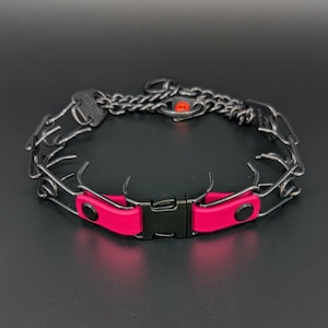 May include: A dog training collar with a chain and prong design. The collar features a bright pink section with a black buckle and accents. The metal components are dark gray.