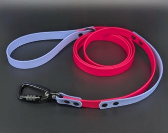 May include: A dual-colored dog leash featuring a light lavender strap and a vibrant hot pink strap. The leash includes a black metal carabiner clip at one end, secured with black rivets, and a loop handle at the other end for a secure grip.