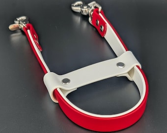 Könnte beinhalten: Ein roter und weißer Leder-Leinen-Griff mit silberfarbenen Metallverschlüssen. Der Griff hat eine gebogene rote Basis mit einem weißen Oberteil, verbunden durch weiße Riemen mit roten Kanten. Die Verschlüsse sind mit Nieten an den Riemen befestigt.