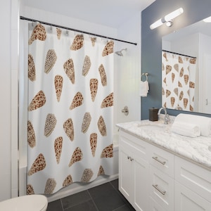 May include: White shower curtain featuring a repeating pattern of brown and tan seashell illustrations. The seashells have a speckled design and are scattered across the curtain. The curtain is hanging in a bathroom setting.