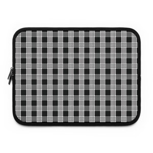 May include: A black and white plaid laptop sleeve with a black zipper and trim. The pattern is a classic gingham design, with alternating black and white squares. The sleeve is rectangular with rounded corners.