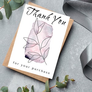 May include: A white thank you card with a watercolor background in shades of pink and purple. A simple line drawing of a branch with leaves is in the center of the card. The text "Thank You" is written in black cursive at the top of the card. The text "for your purchase" is written in black at the bottom of the card.