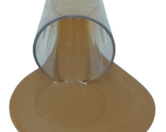 Könnte beinhalten: Ein klares Glas verschüttet braune Flüssigkeit auf eine weiße Oberfläche und bildet eine Pfütze.