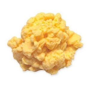 May include: A close-up of a yellow scrambled egg dish. The egg is fluffy and has a light yellow colour.