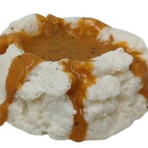 May include: A white, fluffy mashed potato mound topped with a rich, brown gravy. The gravy is drizzled over the potato, creating a visually appealing presentation.