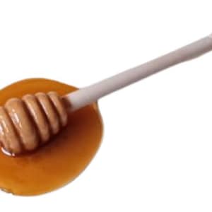 May include: A white plastic honey dipper with a spiral design is dipped into a pool of golden honey.