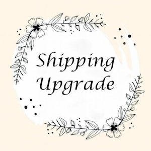 May include: A cream-colored graphic with the words "Shipping Upgrade" in black script, surrounded by a floral wreath of black line art. The design includes leaves, flowers, and small dots.