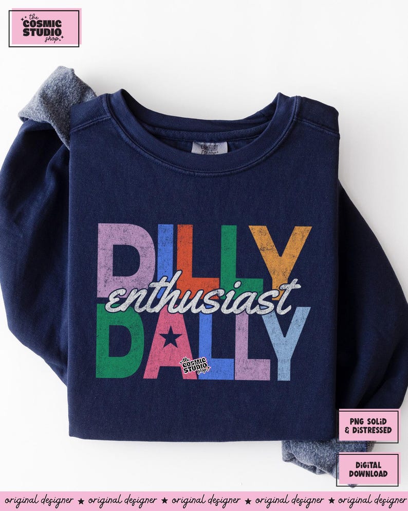 May include: Navy blue sweatshirt with the words "DILLY enthusiast DALLY" in colorful, distressed lettering. The design includes a star and the text "the COSMIC STUDIO shop." Additional text indicates "PNG SOLID & DISTRESSED" and "DIGITAL DOWNLOAD."